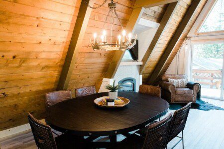 A dining room in a log cabin with wood beams located in Acorn Falls Bass Lake California