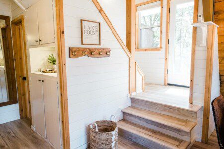 A cozy tiny house with a charming wooden staircase leads to a warm, rustic upper-level ambiance in Acorn Falls, California.