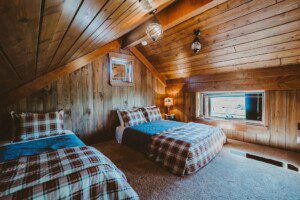 Two-bed setup inside a cozy cabin at Thayne WY Vacation Rentals with rustic decor and comfortable sleeping space for Wyoming travelers.