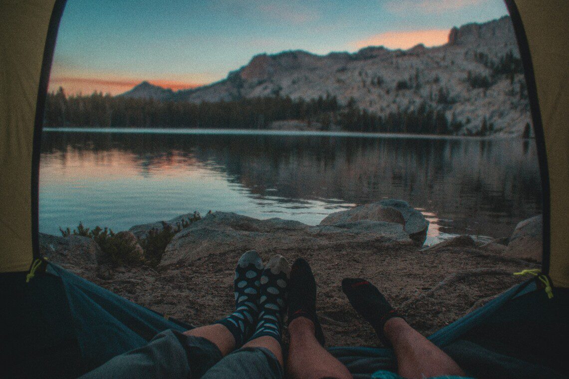 Relaxing after camping in Yosemite, a person’s sock-covered feet rest with a stunning mountain view in the background.