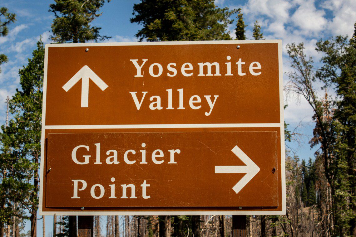 Signage arrow pointing toward Yosemite Valley and Glacier Point, surrounded by snowy landscapes, showcasing the beauty of Yosemite in February