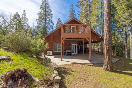 Oakhurst cabin near Yosemite with outdoor deck seating surrounded by forest views