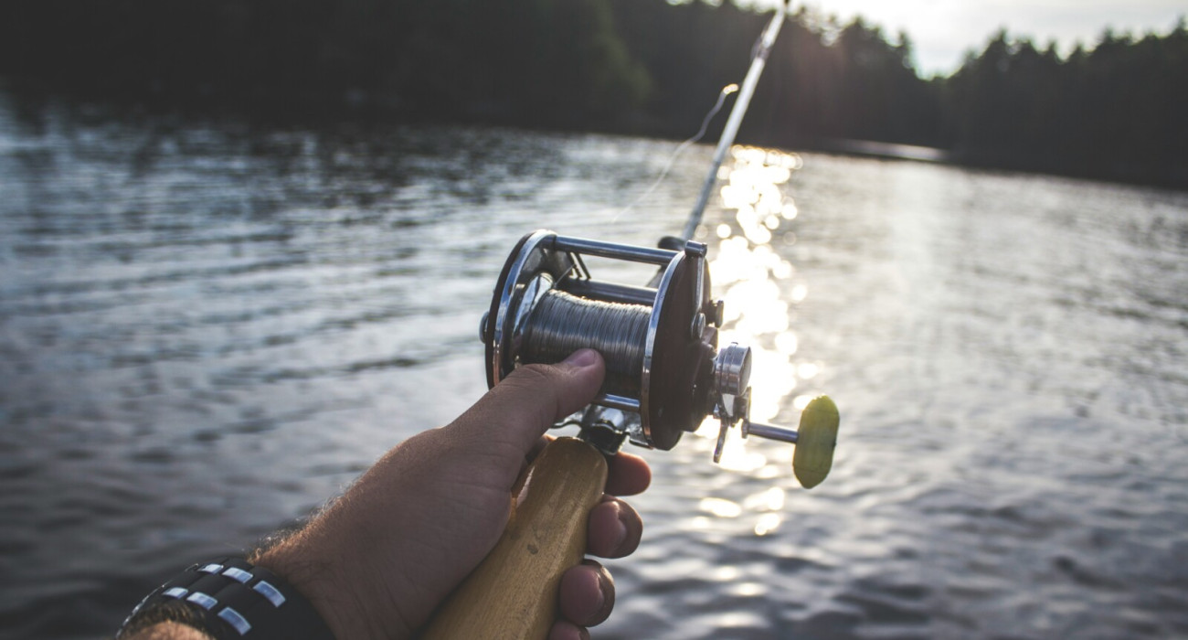 Angler holding a rod on a boat at one of the best fishing spots near Bass Lake CA