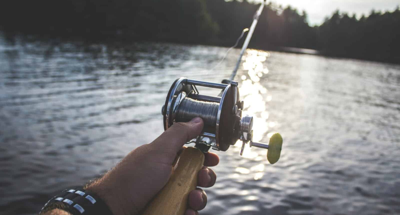 Angler holding a rod on a boat at one of the best fishing spots near Bass Lake CA