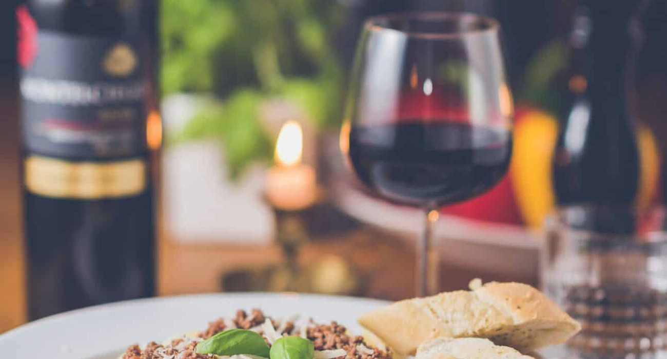 Valentine's Day Dinner at Coarsegold featuring a delicious plate of pasta with bread and a bottle of red wine, perfect for a romantic evening.